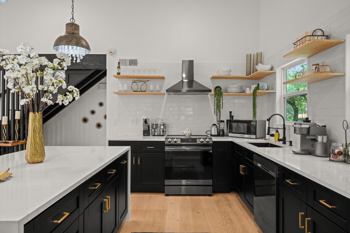 3904 Highland Drive Austin, TX 78734 - Photo 14 of 37 Kitchen featuring dark cabinetry, open shelves, stainless steel appliances, and light stone countertops
