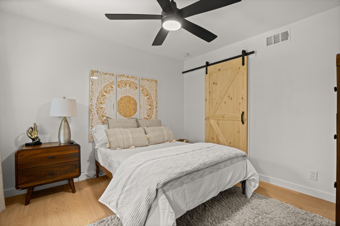 3904 Highland Drive Austin, TX 78734 - Photo 28 of 37 Bedroom featuring ceiling fan, light wood finished floors, and a barn door