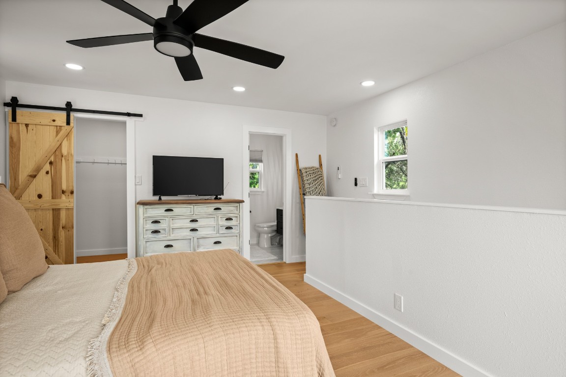 3904 Highland Drive Austin, TX 78734 - Photo 35 of 37 Bedroom with a barn door, light wood-style flooring, a ceiling fan, recessed lighting, and a walk in closet