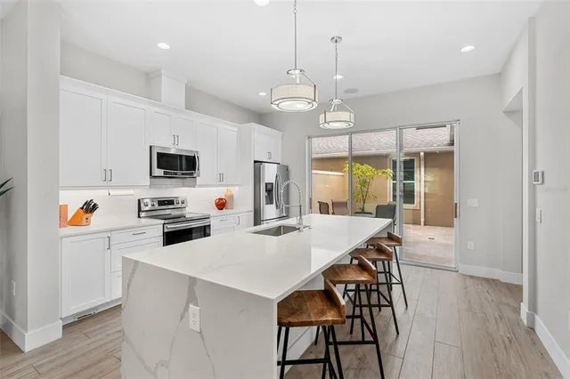 a kitchen with stainless steel appliances a white table chairs and a refrigerator
