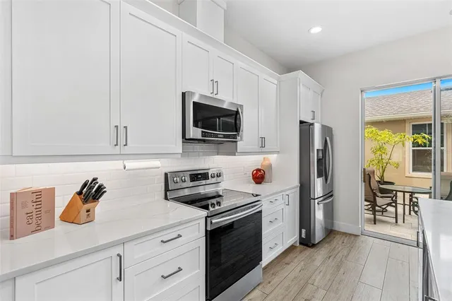 a kitchen with stainless steel appliances white cabinets and wooden floors