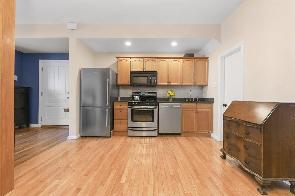 67 Broadway, Unit 1 Chelsea, MA 02150 - Photo 7 of 20 a kitchen with stainless steel appliances a refrigerator a sink a stove a microwave and wooden floor