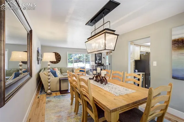 a kitchen with a stove a sink dishwasher a dining table and chairs with wooden floor