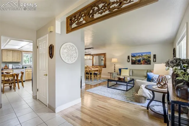a living room with furniture a clock and a view of kitchen