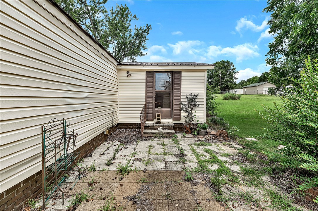 1004 Wiles Road Anderson, SC 29625 - Photo 22 of 26 A modest side entrance leads to a spacious green yard under a bright sky.