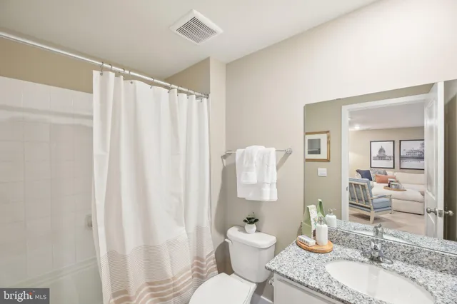 a bathroom with a granite countertop sink and a mirror with toilet