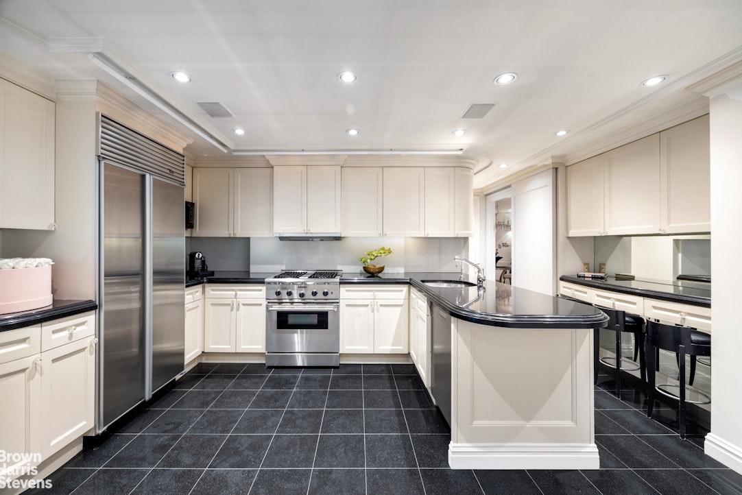 27 East 65th Street, Unit 9DE Manhattan, NY 10065 - Photo 4 of 14 a kitchen with stainless steel appliances granite countertop a sink stove and refrigerator