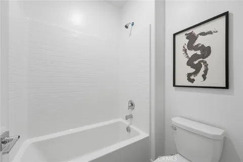 a white bath tub sitting next to a white toilet and vanity