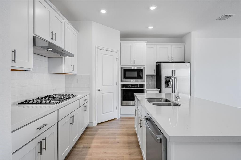 1429 Arciones Road Fort Worth, TX 76052 - Photo 4 of 39 a kitchen with stainless steel appliances a stove a sink a refrigerator and cabinets