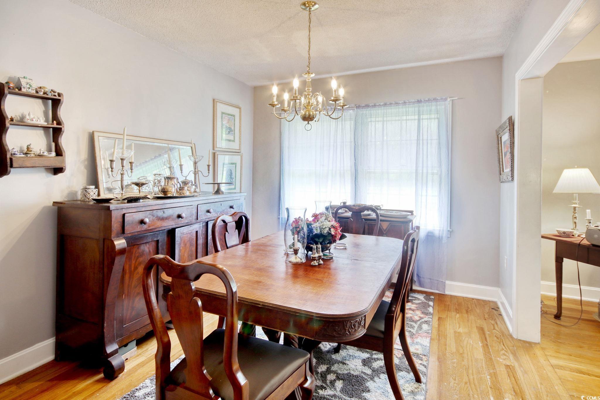 2004 Seitter Street Georgetown, SC 29440 - Photo 11 of 33 Dining space featuring a chandelier, light wood-style flooring, baseboards, and a textured ceiling