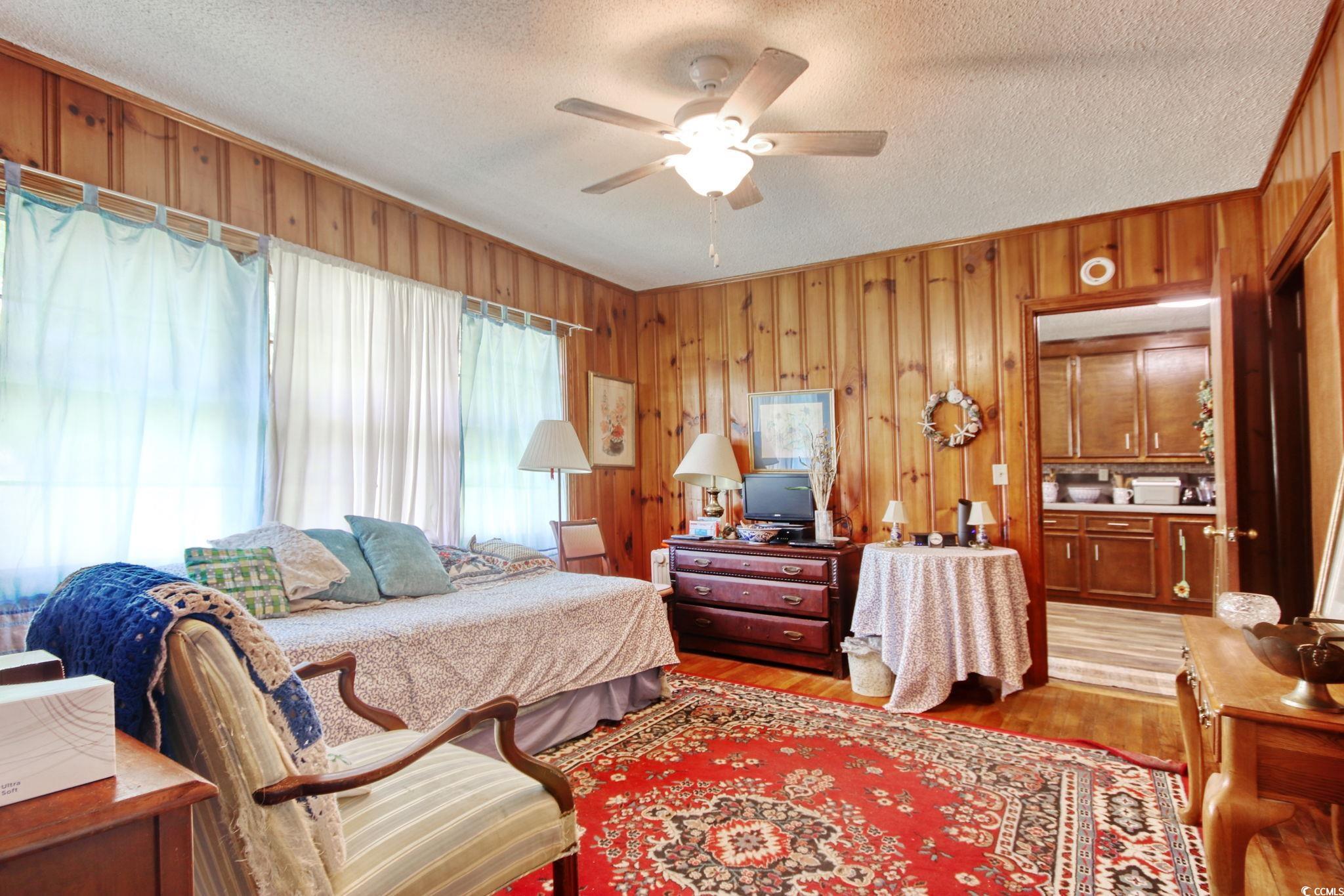 2004 Seitter Street Georgetown, SC 29440 - Photo 18 of 33 Bedroom featuring light wood-style flooring, wood walls, a textured ceiling, and a ceiling fan