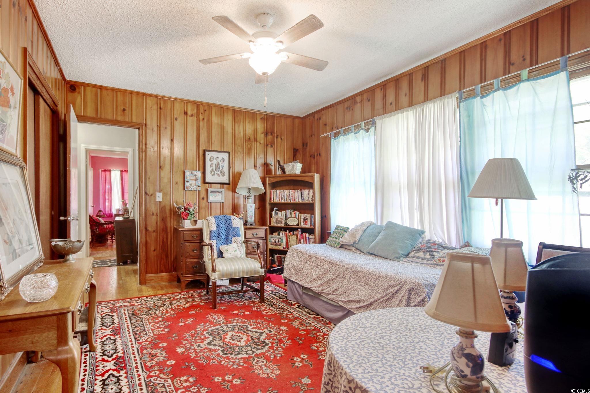2004 Seitter Street Georgetown, SC 29440 - Photo 19 of 33 Bedroom featuring wood finished floors, wooden walls, a textured ceiling, ornamental molding, and ceiling fan