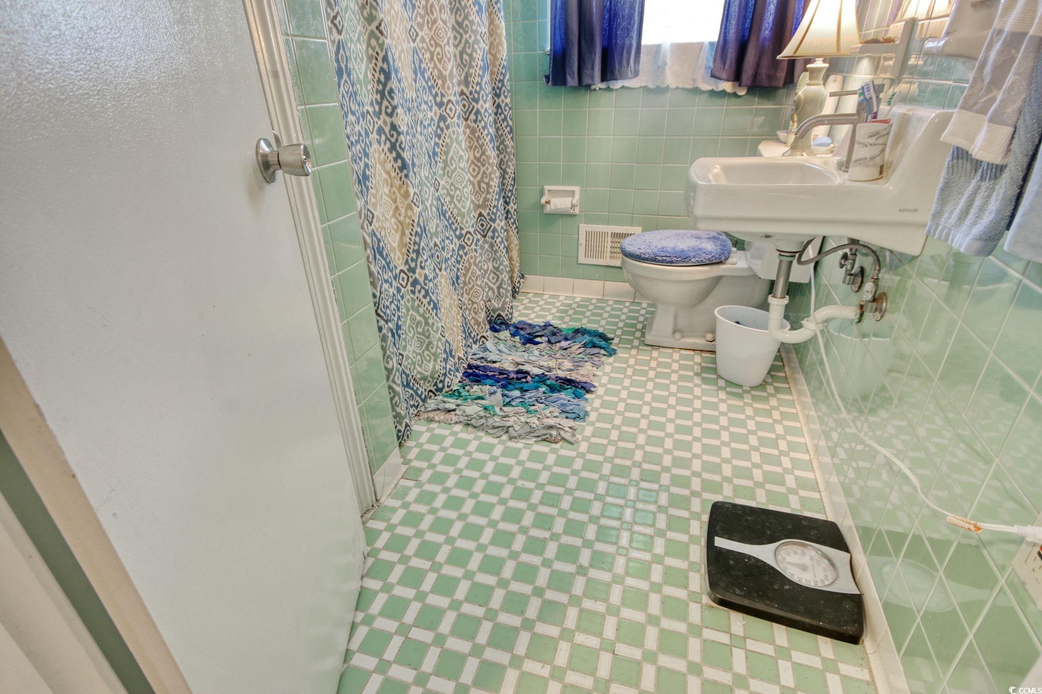 2004 Seitter Street Georgetown, SC 29440 - Photo 21 of 33 Full bathroom with toilet, curtained shower, tile walls, tile patterned floors, and a sink