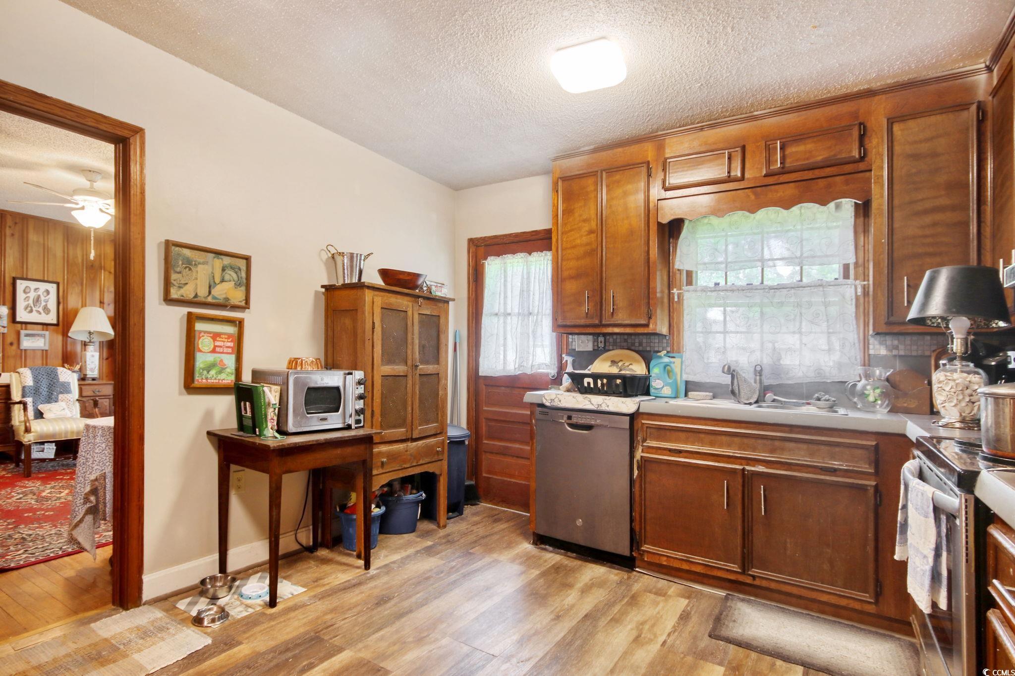 2004 Seitter Street Georgetown, SC 29440 - Photo 9 of 33 Kitchen with stainless steel appliances, a textured ceiling, light wood-style flooring, tasteful backsplash, and light countertops