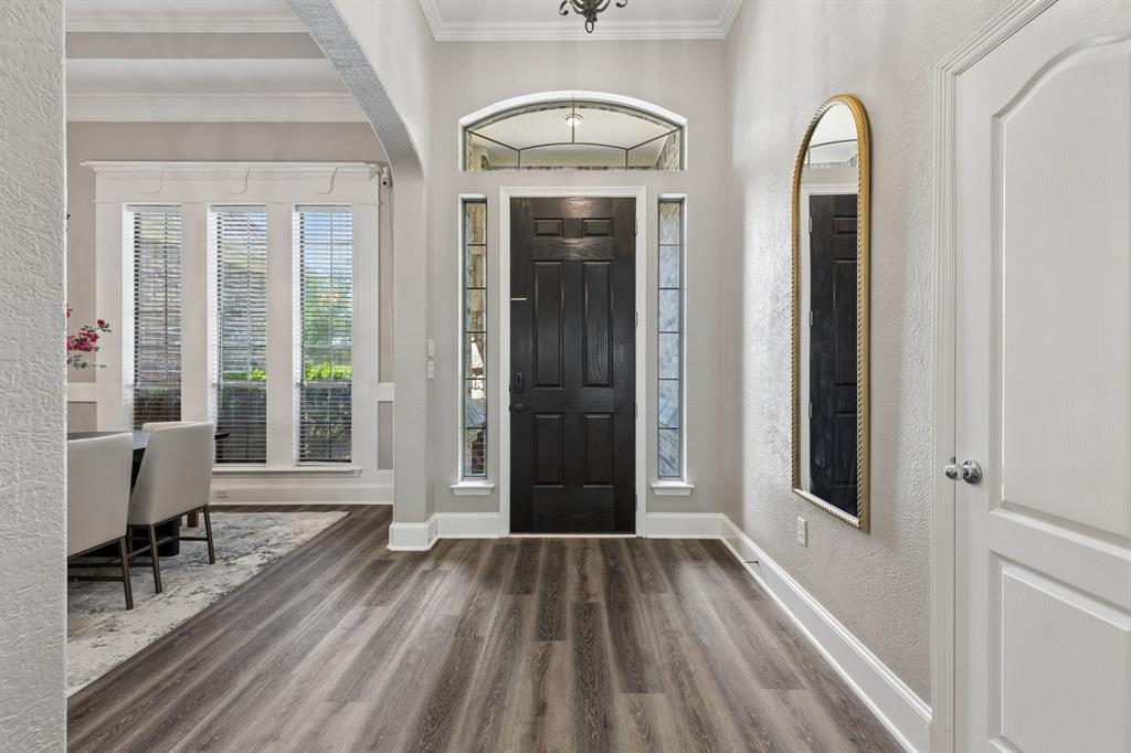 317 Singing Quail Trail Haslet, TX 76052 - Photo 5 of 32 Entryway featuring a dark paneled door with an arched transom window and sidelights, wood-finish flooring, and white trim throughout