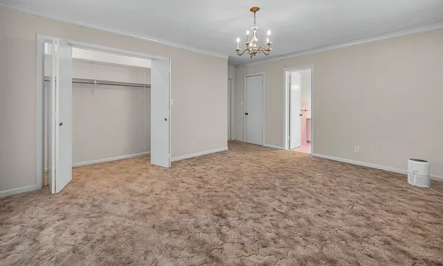 a view of an empty room and chandelier fan