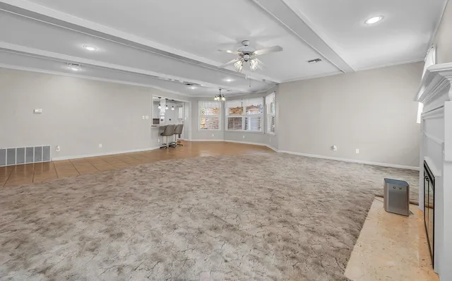 an empty room with chandelier fan and windows