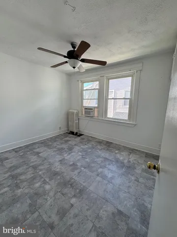 an empty room with windows and fan