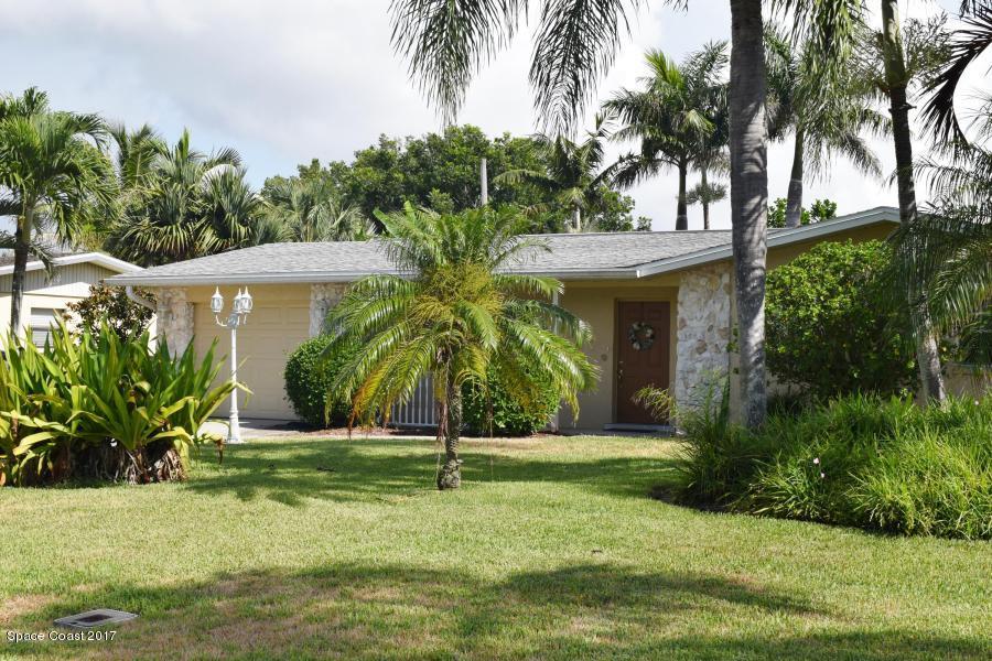 a view of a white house with a yard and palm trees