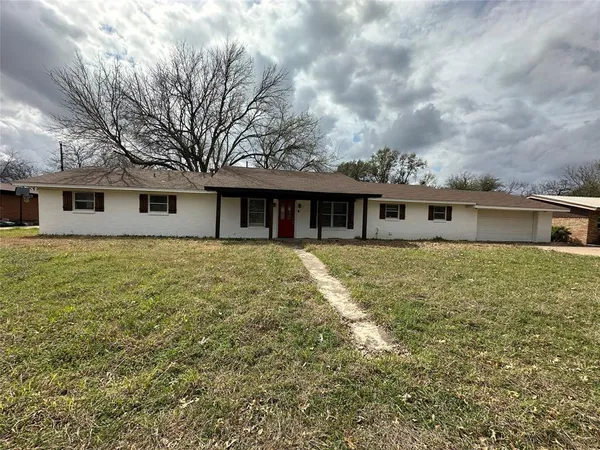 a front view of house with yard and trees around