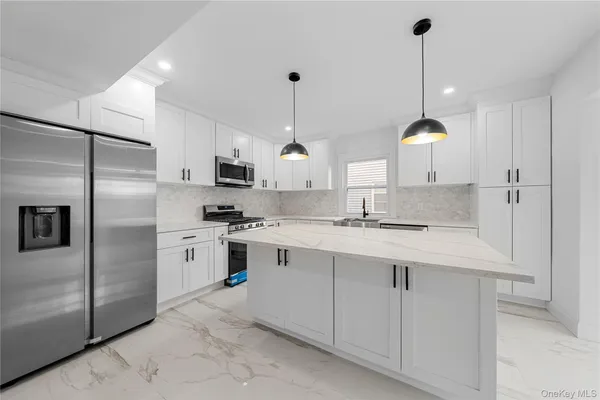 a kitchen with stainless steel appliances granite countertop a sink a stove a refrigerator and island