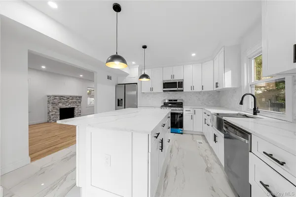 a large kitchen with kitchen island a stove a sink a center island a stove a refrigerator cabinets and living room view