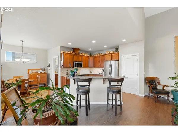 a kitchen with stainless steel appliances kitchen island granite countertop a table chairs and a refrigerator