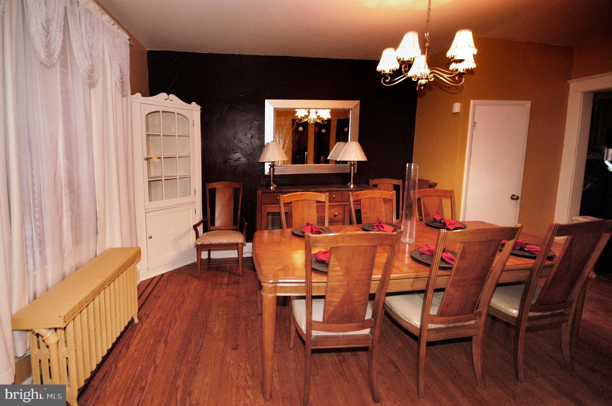 2417 North Pulaski Street Baltimore, MD 21217 - Photo 8 of 26 a dining room with wooden floor a chandelier a glass table and chairs