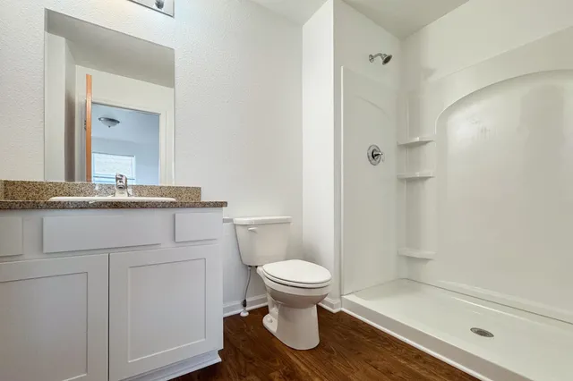 a bathroom with a granite countertop toilet a sink and a mirror