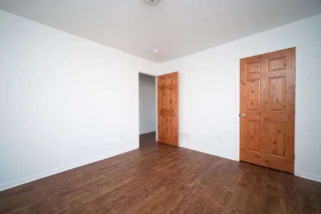 an empty room with wooden floor & closet area