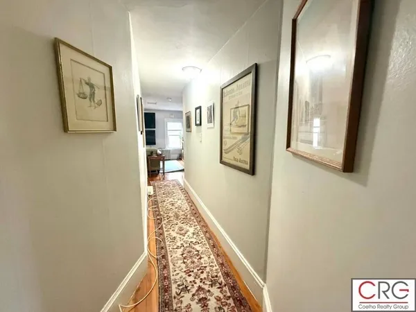 a view of a hallway with wooden floor and a livingroom