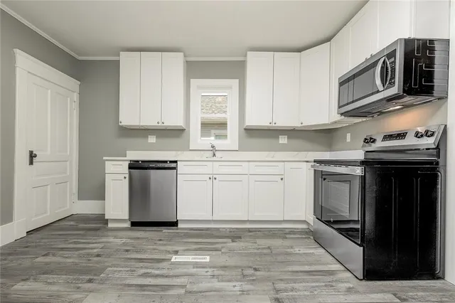 a kitchen with stainless steel appliances granite countertop a stove a sink and a microwave