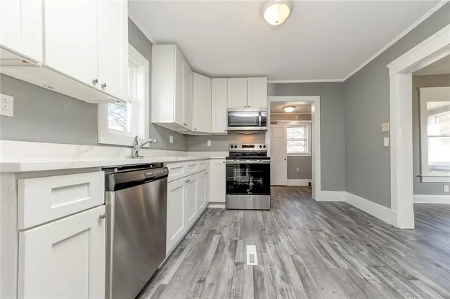 a kitchen with stainless steel appliances granite countertop a stove top oven a sink dishwasher and a refrigerator with wooden floor