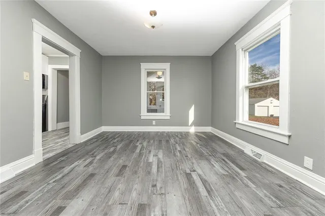 a view of an empty room with wooden floor and a window