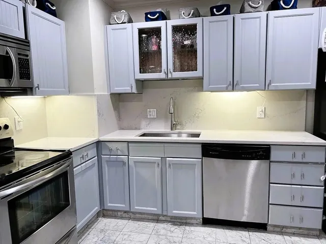 a kitchen with granite countertop white cabinets and stainless steel appliances