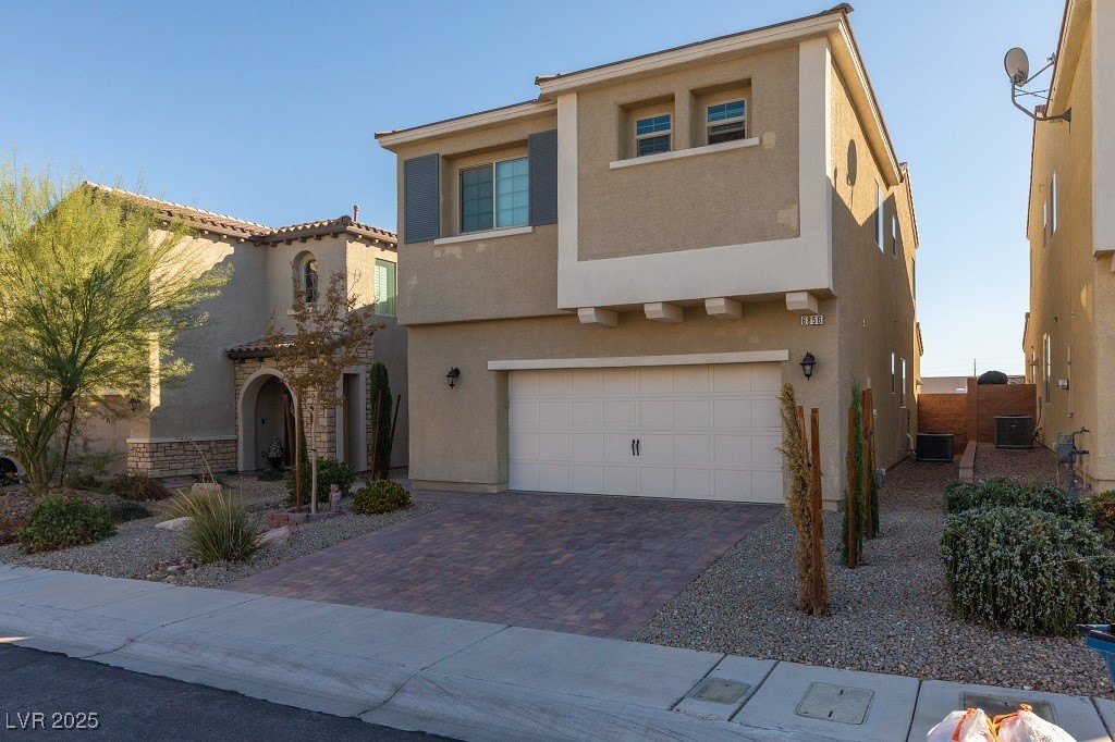 Mediterranean / spanish-style house with stucco siding, an attached garage, and decorative driveway
