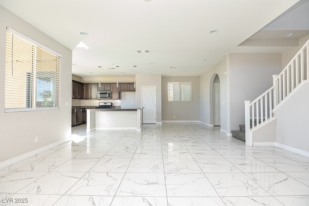 6856 Pivot Point Street Las Vegas, NV 89148 - Photo 11 of 32 Unfurnished living room with healthy amount of natural light, light marble finish flooring, stairway, arched walkways, and recessed lighting