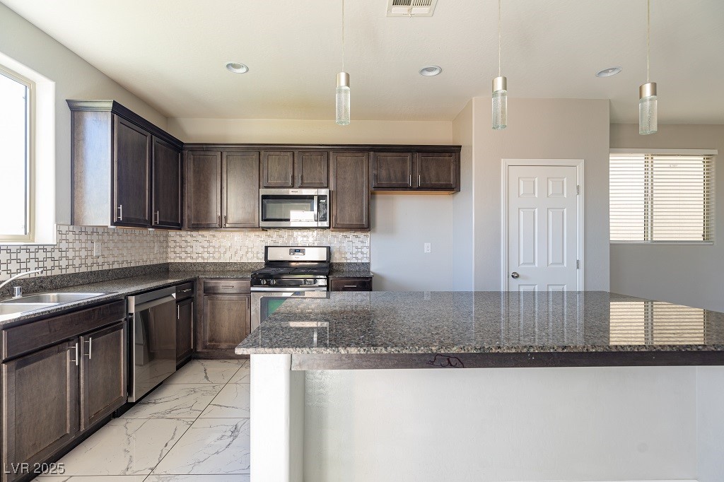 6856 Pivot Point Street Las Vegas, NV 89148 - Photo 18 of 32 Kitchen with dark brown cabinetry, light marble finish floors, stainless steel appliances, pendant lighting, and recessed lighting