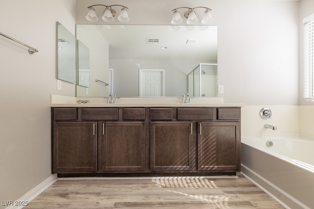 6856 Pivot Point Street Las Vegas, NV 89148 - Photo 24 of 32 Full bathroom with double vanity, a bath, a shower stall, and light wood-style floors