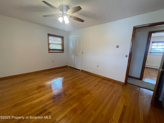 a view of an empty room with a window and wooden floor