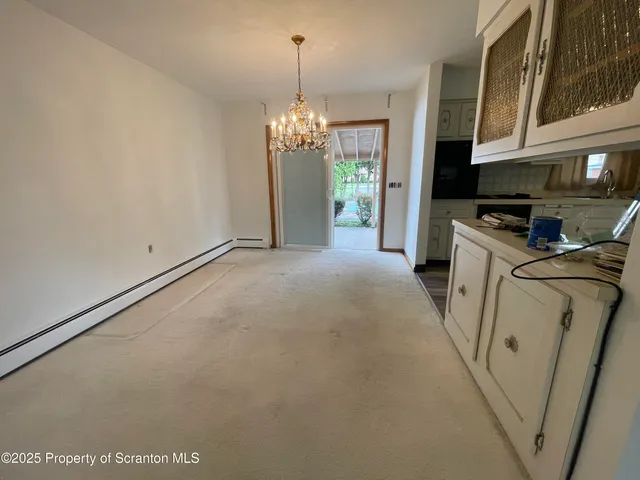 a view of a kitchen with a sink a refrigerator a kitchen island a stove and a chandelier