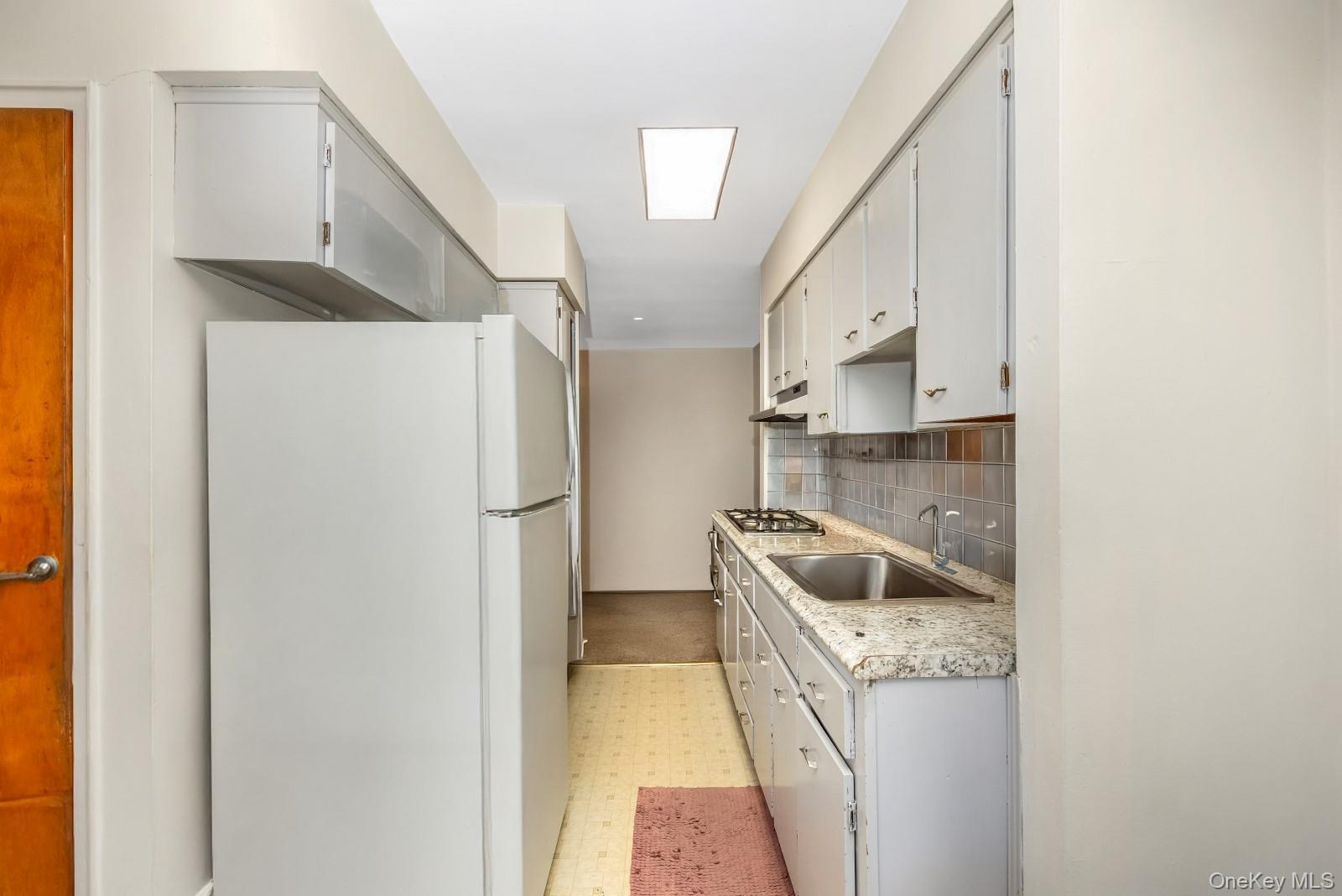 60-56 75th Street Queens, NY 11379 - Photo 16 of 30 a kitchen with a refrigerator sink and cabinets