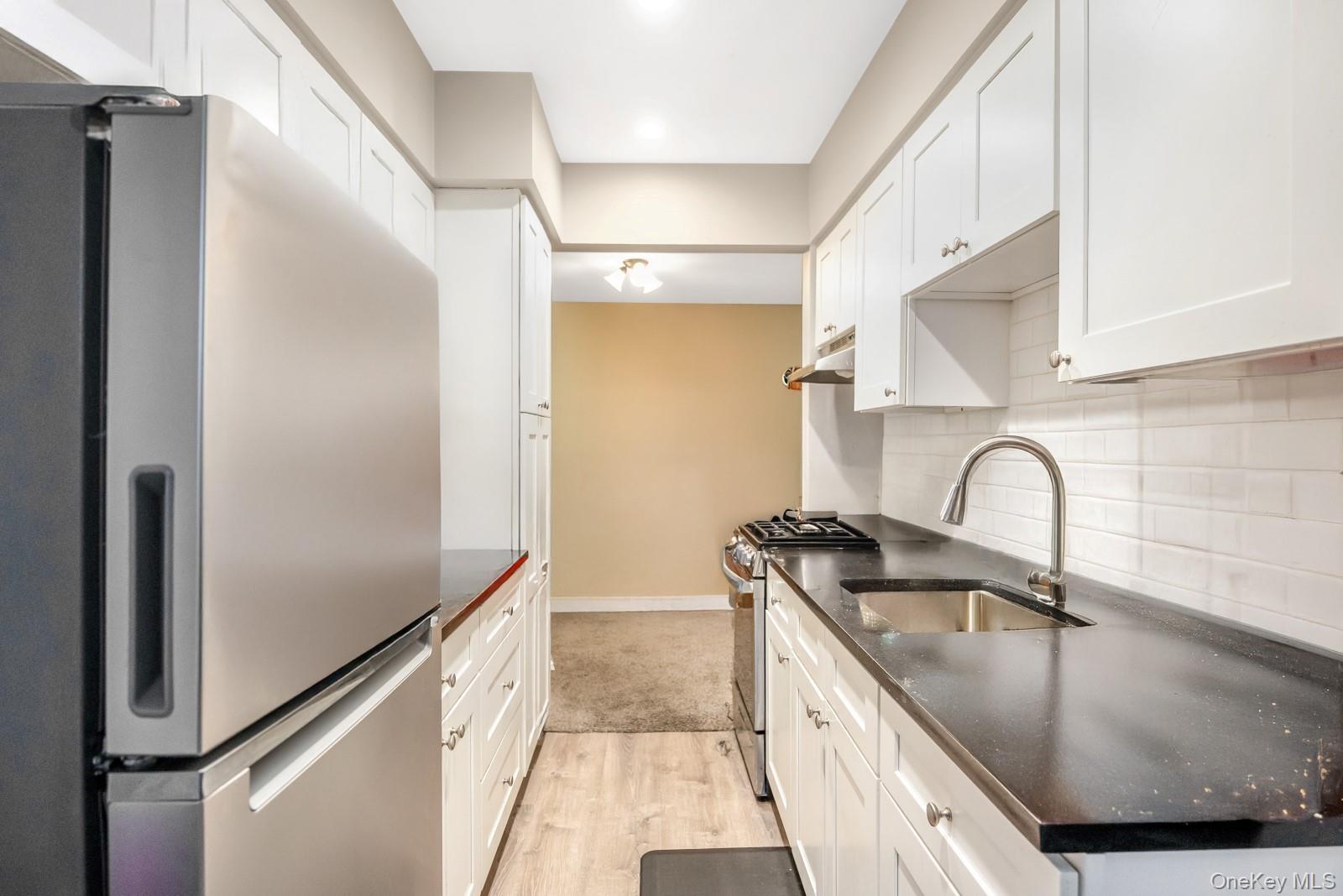 60-56 75th Street Queens, NY 11379 - Photo 9 of 30 a kitchen with granite countertop a sink stainless steel appliances and cabinets