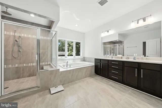 a spacious bathroom with a tub sink shower and mirror