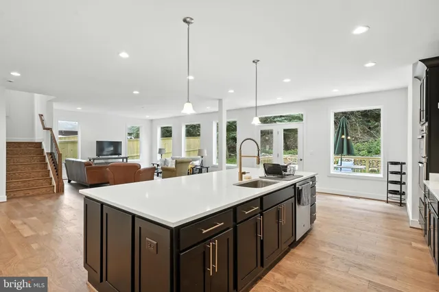 a kitchen with a stove a sink a kitchen island a window and chairs