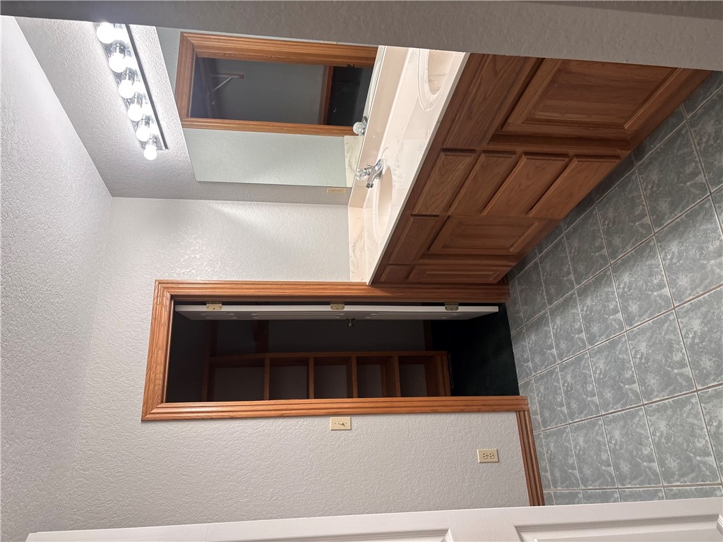15262 Shipe Road Gravette, AR 72736 - Photo 34 of 60 Double vanity with integrated sinks, wood-finish cabinetry, full-width mirror, and a multi-bulb light fixture