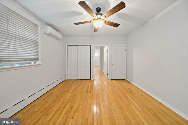 a view of an empty room with chandelier fan and wooden floor