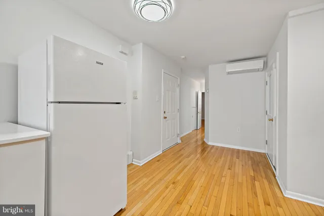 a view of a room with wooden floor and a refrigerator