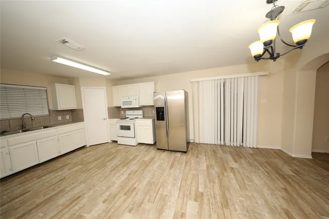 a large white kitchen with cabinets a sink a window and stainless steel appliances