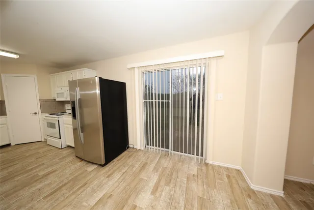 a view of a kitchen with refrigerator and wooden floor